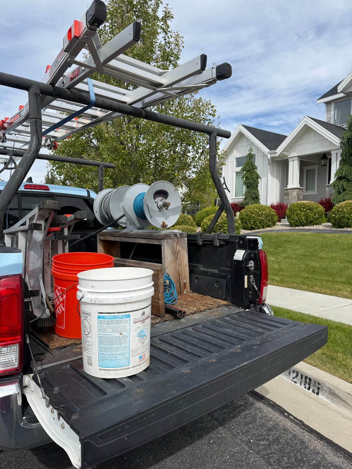 Buckets, a hose reel, and ladders loaded on a Glide service truck for exterior cleaning work