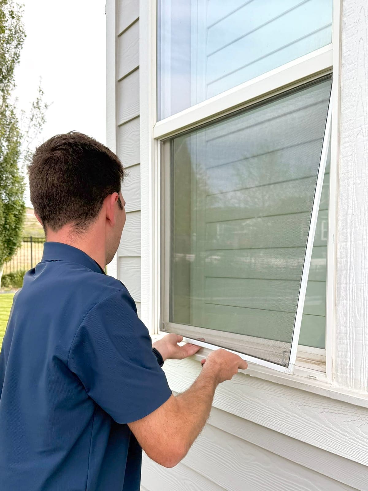 Technician cleaning a window screen mesh by hand