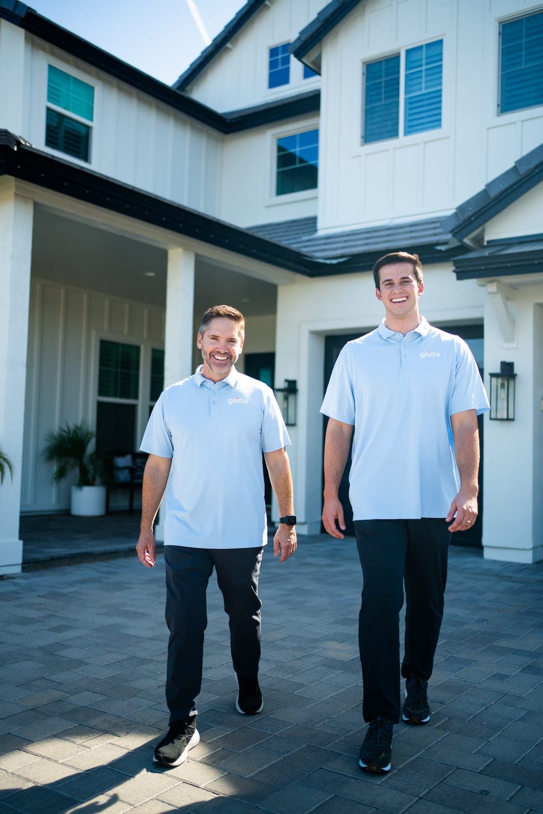 Two Glide technicians walking up to a home to start a scheduled window cleaning visit