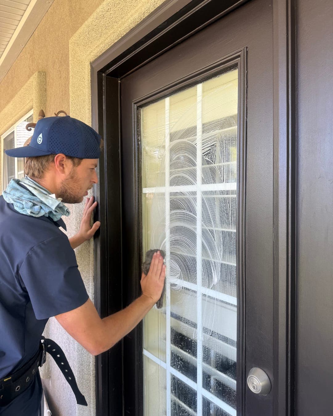 Glide technician hand-detailing the glass panes of a back door from outside the home